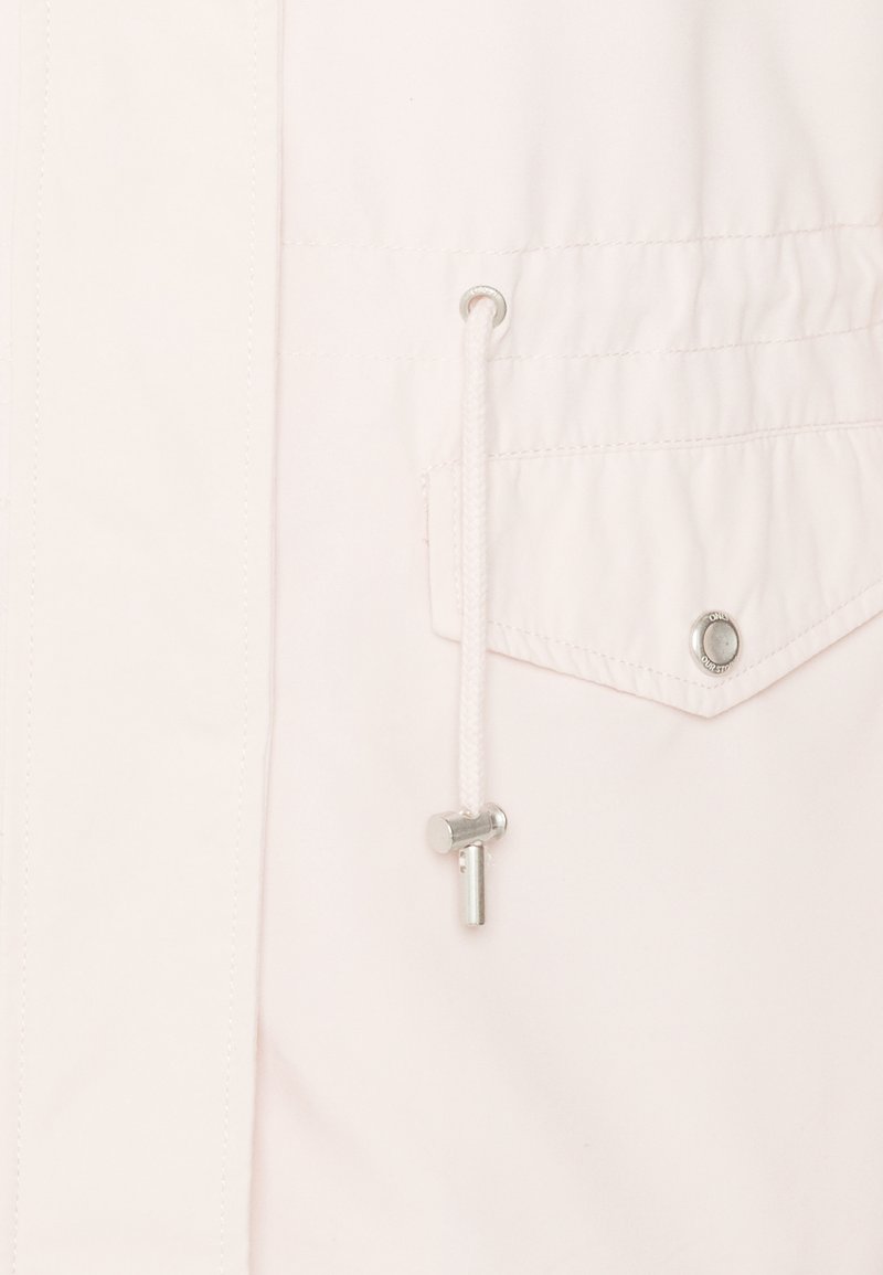 Tissu blanc avec un cordon passant dans un œillet métallique et un rabat de poche boutonné avec un bouton-pression métallique.