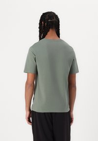 Tricou cu mânecă scurtă din bumbac verde măsliniu, cu decolteu rotund și croială dreaptă. Caracteristici: o etichetă mică la tiv. Textură fără îmbinări.