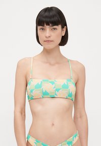 Bikini gornji dio s geometrijskim cvjetnim uzorkom u pastelnim bojama na zelenoj pozadini. Podesive naramenice i bandeau dizajn.