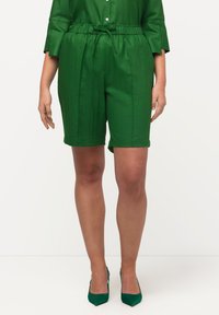 Shorts verdi con vita elastica, realizzati in tessuto testurizzato con finitura liscia, caratterizzati da una vestibilità rilassata e tasche laterali.