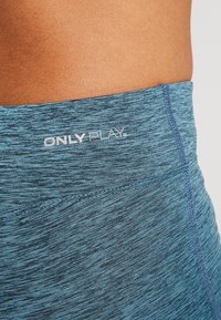 Niebieskie szorty sportowe z teksturowanej tkaniny o heatherowym wzorze. Widoczny elastyczny pas z logo "ONLY PLAY".