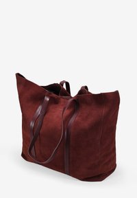 Bolso tote de ante en burdeos intenso con superficie texturizada, forma alargada y dos asas de cuero en contraste. Sin detalles visibles de herrajes.