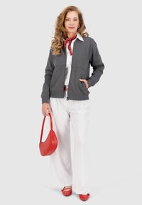 Felpa grigia con zip e tasche laterali, maglietta bianca, pantaloni bianchi a gamba larga, borsa rossa e scarpe rosse. Texture liscia e design casual.