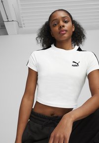 Witte cropped t-shirt met contrasterende zwarte schouderaccenten en Puma-logo. Gemaakt van gladde stof, met een ronde halslijn en korte mouwen.