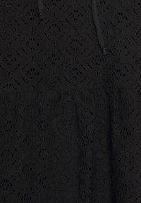 Tissu noir avec un motif complexe de dentelle florale et un détail à cordon cousu au centre en haut.