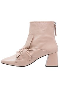 Rosa läderankelstövel med en knutdetalj framtill, spetsig tå och kraftig klack. Sidodragkedjeöppning för enkel påtagning.
