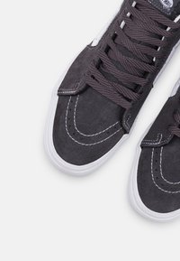 Gråmockasiner med vita gummisulor, som har rund snörning, dekorativ sömnad och en klassisk silhuett.