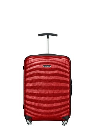 Roter Hartschalenkoffer mit welliger Textur, teleskopischem Griff und vier Rollen für Mobilität. Markenlogo an der Vorderseite sichtbar.