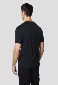 T-shirt noir à manches courtes en coton, avec un col rond. Logo de la marque visible sur la manche gauche. Texture lisse et coupe ajustée.