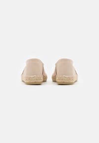 Nude Wildlederschuhe mit natürlicher Jutessohle, glatter Textur, runder Zehenpartie und genähter Detailverarbeitung entlang der Kanten.