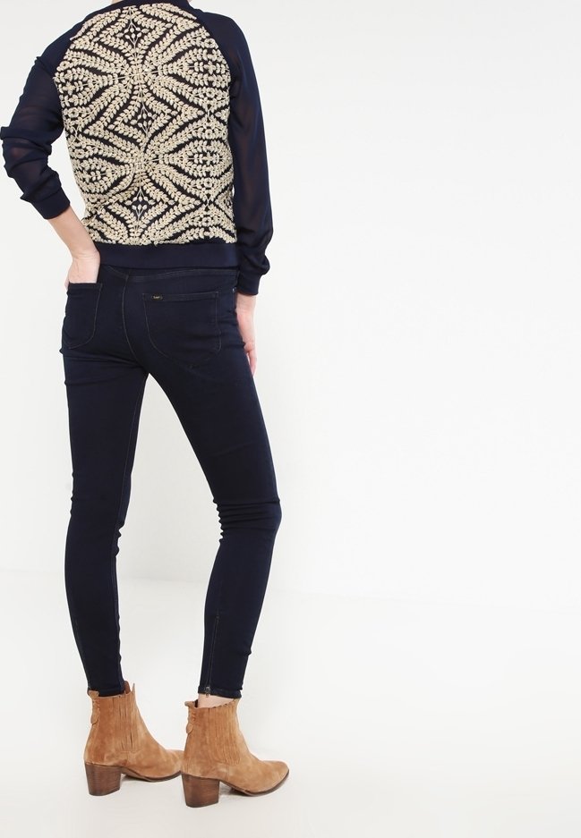 Marinblå tröja med beige blommönster broderat på ryggen, i kombination med mörk denimskinnyjeans och bruna ankelboots.