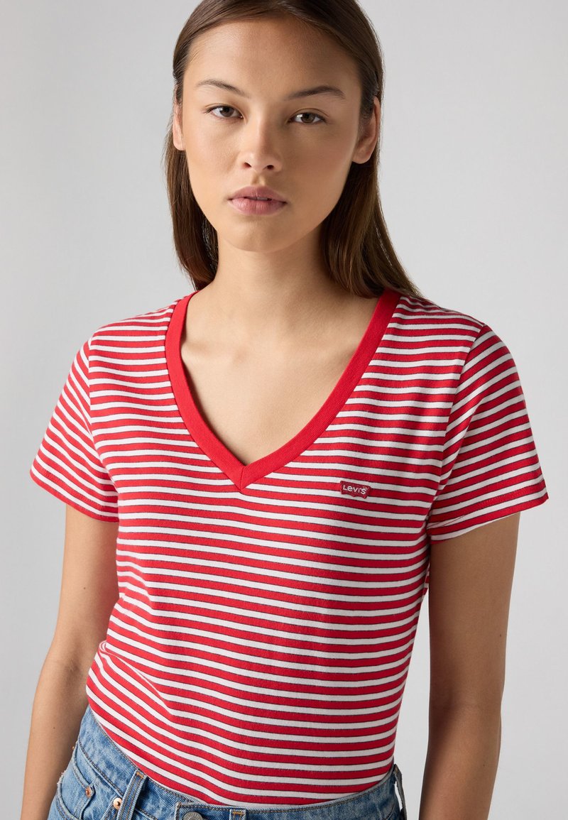 Rot-weiße gestreifte kurzärmelige T-Shirt mit V-Ausschnitt, mit einem kleinen Levi's Logo auf der linken Brust. Aus Baumwollmaterial.