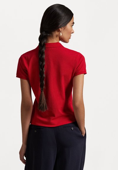 Red polo shirt with a flat collar and short sleeves. Smooth fabric texture, featuring a fitted design and a slight curve at the back.