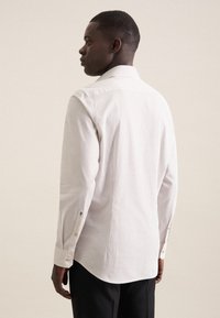 Chemise blanche à petit motif à pois noirs, à manches longues, avec des poignets boutonnés et un col classique, conçue pour un ajustement slim.