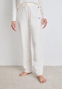 Pantalons lounge blancs en tissu doux avec taille élastique et cordon de serrage, dotés de poches latérales et d'un discret logo "BOSS" noir.
