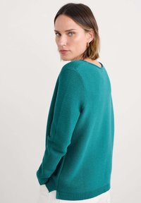 Teal gebreide trui met geribbelde textuur, ronde halslijn en een iets losse pasvorm. Beschikt over lange mouwen en een rechte snit aan de onderkant.