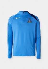 Lysblå langærmet træningstrøje med halv-zip krave, der har mørkeblå accenter, et Nike-logo og en klubemblem på brystet.