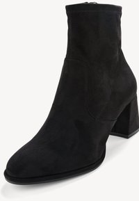 Bottine en daim noir avec bout arrondi et talon bloc, présentant des détails cousus le long des côtés et du bord supérieur.