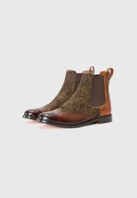 Botas Chelsea de cuero marrón con paneles laterales de tejido texturizado, punteras redondeadas, perforaciones decorativas y lazos en la parte posterior.