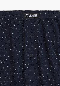 Granatowe bokserki wykonane z bawełny, z małym wzorem liści, elastycznym pasem, zapinanym rozporkiem oraz metką marki na wysokości talii.