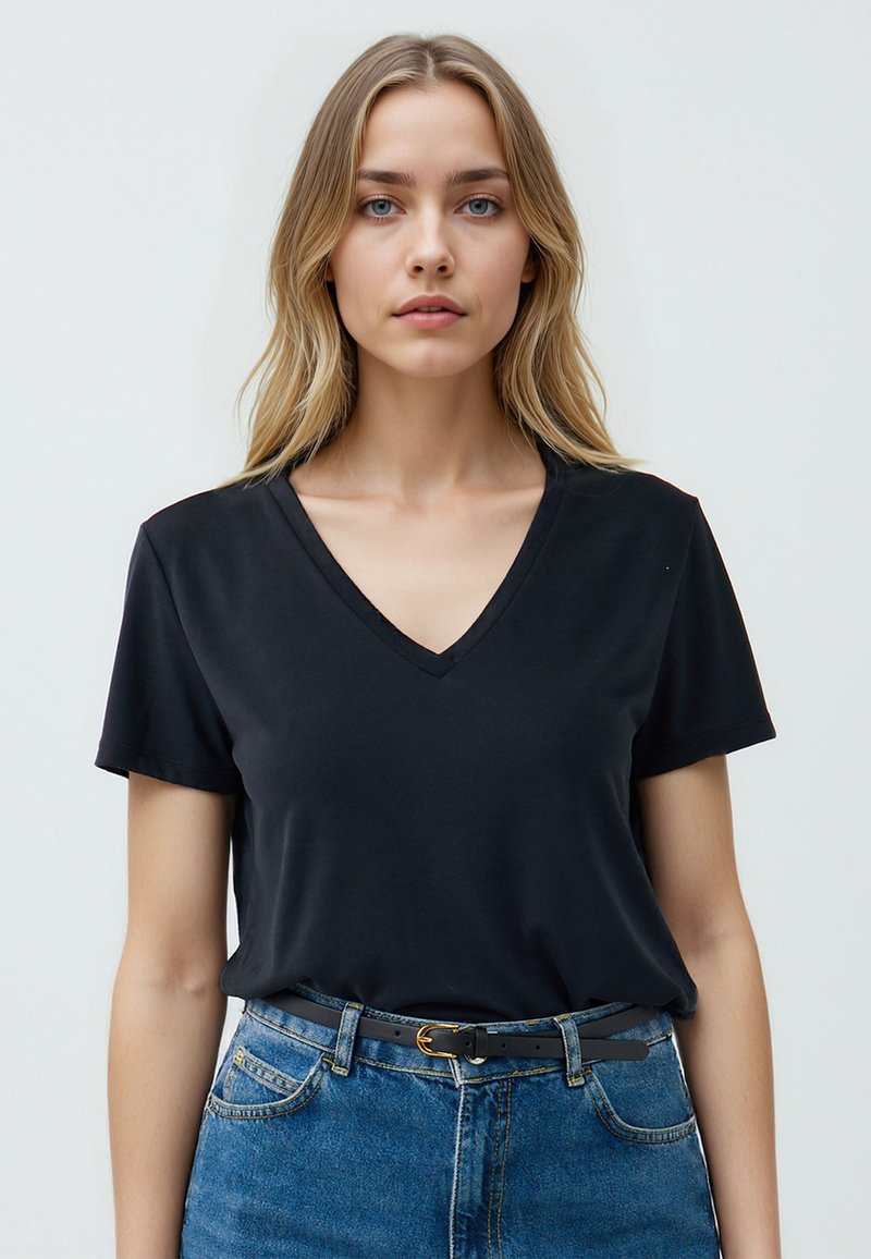 T-shirt nera a V con maniche corte, realizzata in tessuto liscio; abbinata a jeans blu in denim a vita alta e una cintura nera con fibbia dorata.