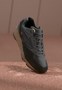 Black and gray sneaker with a textured upper, featuring mesh and suede materials, a rubber sole, and subtle branding.