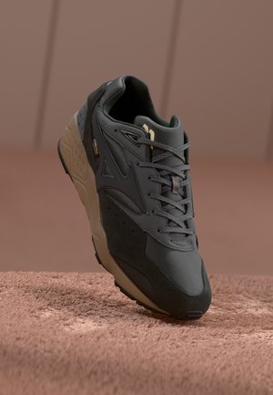 Crne i sive tenisice s teksturiranim gornjim dijelom, koje sadrže mrežaste i antilop materijale, gumeni potplat i suptilnu oznaku branda.