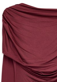 Bordo värvi kangas, millel on sile tekstuur, esitleb lahti rippuvaid voltidega, luues asümmeetrilise kujunduse. Nähtavat riistvara või kaunistusi pole.