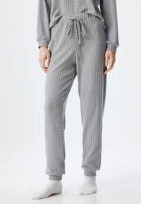 Pantaloni felpati grigi con un elastico in vita e cordoncino regolabile. Il materiale ha una consistenza morbida e presenta design a righe verticali.