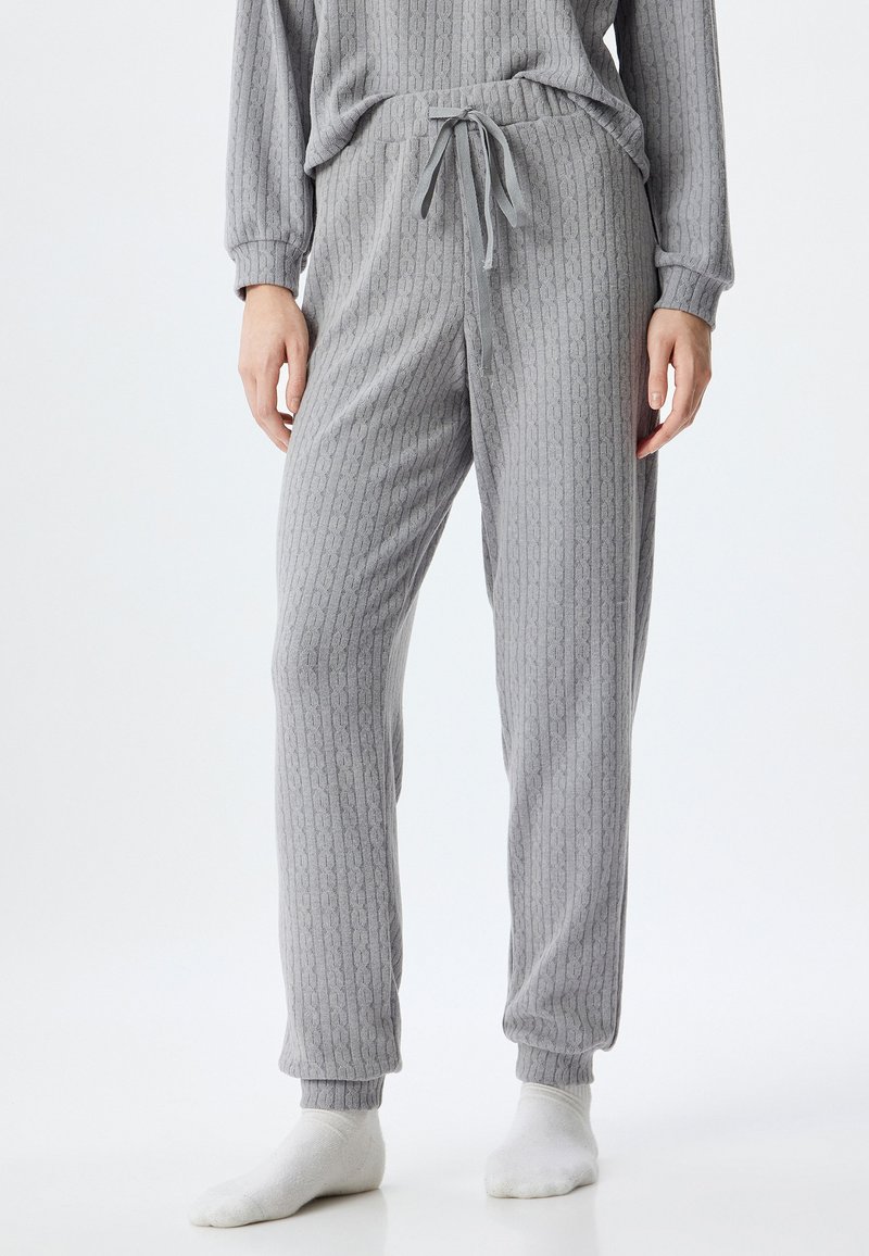 Pantaloni felpati grigi con un elastico in vita e cordoncino regolabile. Il materiale ha una consistenza morbida e presenta design a righe verticali.