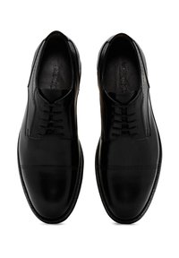 Chaussures de ville en cuir noir avec une finition lisse, présentant un design à lacets et des perforations subtiles au niveau des orteils.