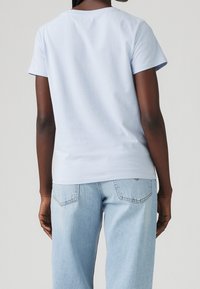 Světle modré bavlněné tričko s krátkým rukávem, kulatým výstřihem a rovného střihu, v kombinaci se světle modrými džínami. Jednoduchý design.