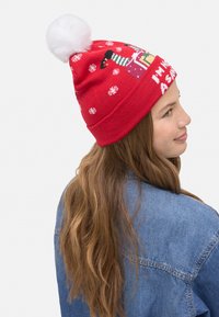 Gorro de punto rojo con pompón blanco, con patrones de copos de nieve y un diseño festivo que dice "No estoy listo para la Navidad."