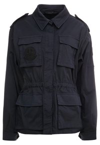 Chaqueta de trabajo azul marino con cierre de botones, cintura elástica, cuatro bolsillos frontales y hombreras. Presenta un parche circular negro.