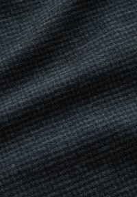 Zbliżenie na ciemnoszary materiał o teksturowanym, ciasno tkanowym wzorze oraz subtelnych diagonalnych cieniach podkreślających detale powierzchni.