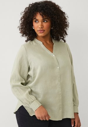 Light green, long-sleeved shirt with a v-neck and button closures. Fabric has a soft, textured finish, and the hem is slightly curved.