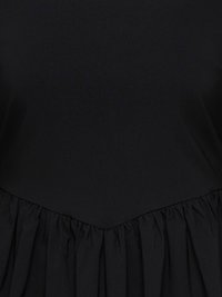 Svart plagg med innsvingt liv og et innsamlingsdel til skjørt som skaper en rysjet, teksturert søm under midjen.