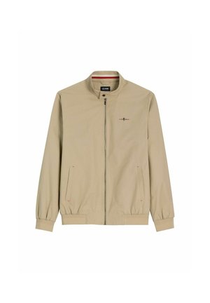 Beżowa kurtka zapinana na zamek z stojącym kołnierzem, elastycznymi mankietami i dołem, dwoma przednimi kieszeniami oraz małym haftowanym logo na piersi.