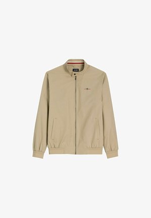 Beżowa kurtka zapinana na zamek z stojącym kołnierzem, elastycznymi mankietami i dołem, dwoma przednimi kieszeniami oraz małym haftowanym logo na piersi.