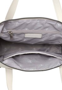 El interior del bolso blanco presenta un forro de tela gris con un patrón de logo sutil, un bolsillo con cremallera y un compartimento principal espacioso.