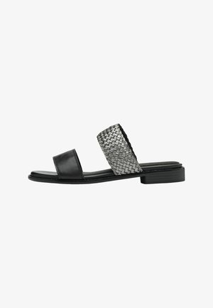 Sandale en cuir noir avec une lanière tissée en argent. Semelle plate avec un design à bout carré et des accents minimalistes.