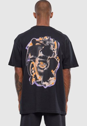 Sort bomuld t-shirt med et farverigt grafisk print på ryggen, der viser abstrakte menneskesilhuetter med orange og lilla nuancer.