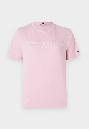 Vaaleanpunainen puuvillapaita, jossa on pyöreä kaula-aukko, lyhyet hihat ja valkoinen painettu logo "TOMMY HILFIGER EST. 1985" rinnassa.