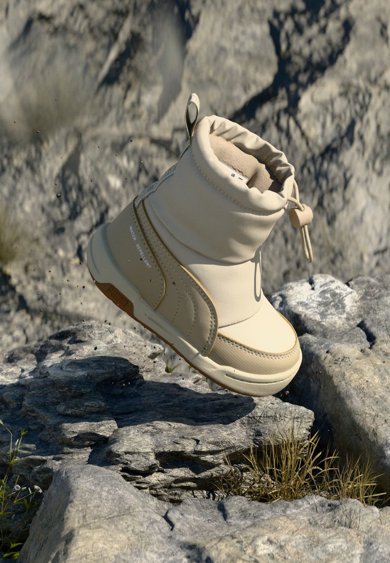Beige waterdichte enkellaars met een gevoerd kraagje, ronde neus en gestructureerde zool, voorzien van een trekhaak en subtiele branding aan de zijkant.