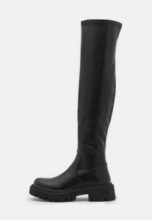 Wysoki czarny skórzany kozaki z grubą, rowkowaną podeszwą i zaokrąglonym noskiem, sięgający powyżej kolana, przedstawiony z boku na białym tle.