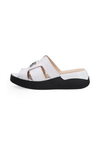 Hvide åben-tå slide sandaler med et krydset stropdesign, sort sål og metallisk detalje på overdelen. Glat lædertekstur.