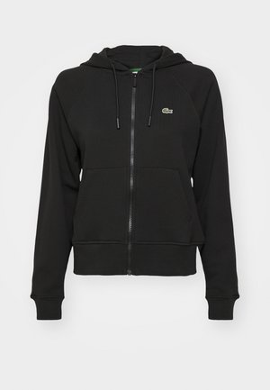 Schwarze Zip-Hoodie aus weichem Stoff, ausgestattet mit einer Kängurutasche, gerippten Bündchen und einem kleinen grünen Logo auf der oberen linken Brust.