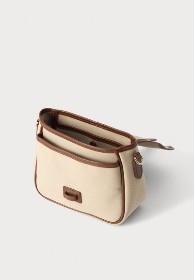 Sac à main en tissu beige avec garniture en cuir marron et anneau doré, ouverture supérieure, forme rectangulaire et poche avant sur fond blanc.