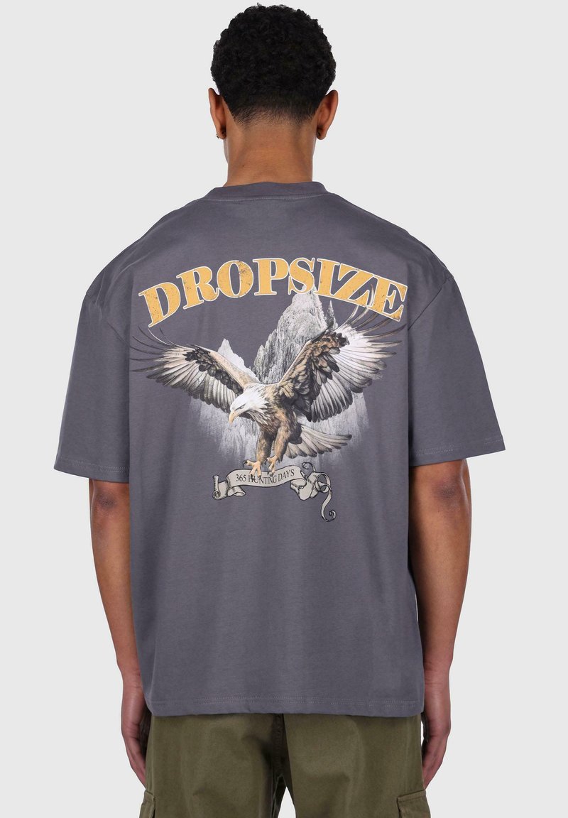 Gray cotton t-shirt featuring a large eagle graphic and mountains. Text reads "DROPSIZE" above, "365 HUNTING DAYS" on a banner below.