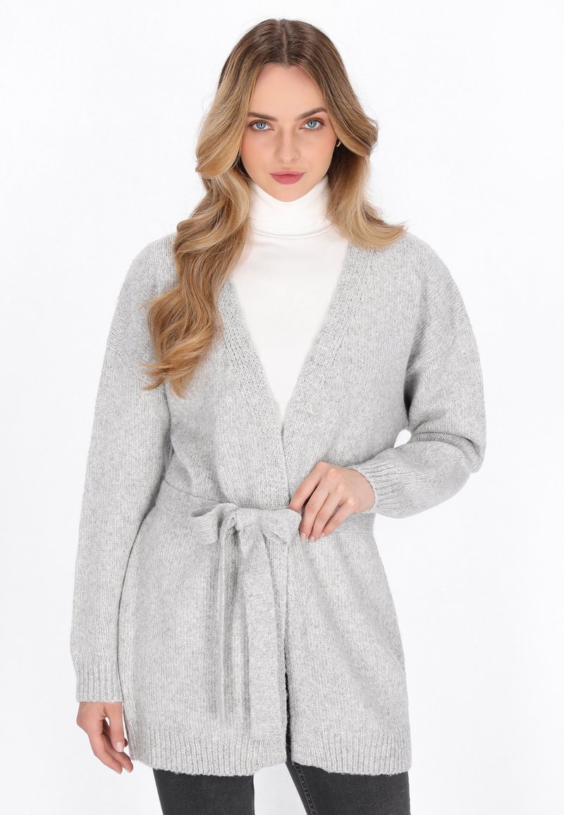 Grå stickad cardigan med bälte i midjan, långa ärmar och öppen framsida. Har en mjuk textur samt ribbad nederkant och ärmslut.
